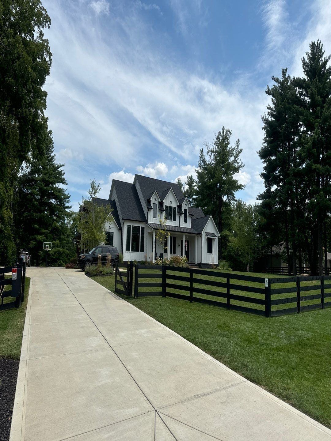Two story Carmel home behind a black rail fence with a cleaned concrete walk