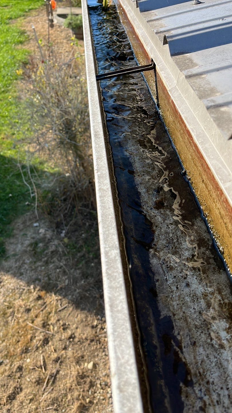 Water running clear along a gutter trough after the debris has been removed